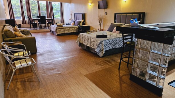 A spacious living area with a sofa, two beds, a dining table, and a bar area.