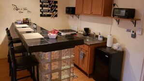 A compact kitchen with a central island, a microwave, a coffee machine, and a refrigerator.