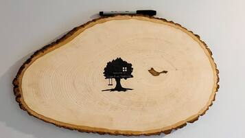 Una rebanada de madera con el silueta negra de un árbol y un pájaro, y un marcador encima.