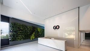 A modern reception area with a marble reception desk, a vertical garden, and a logo for 'GO Living & Suites'. - Go Living and Suites by Jalo (Medellín)