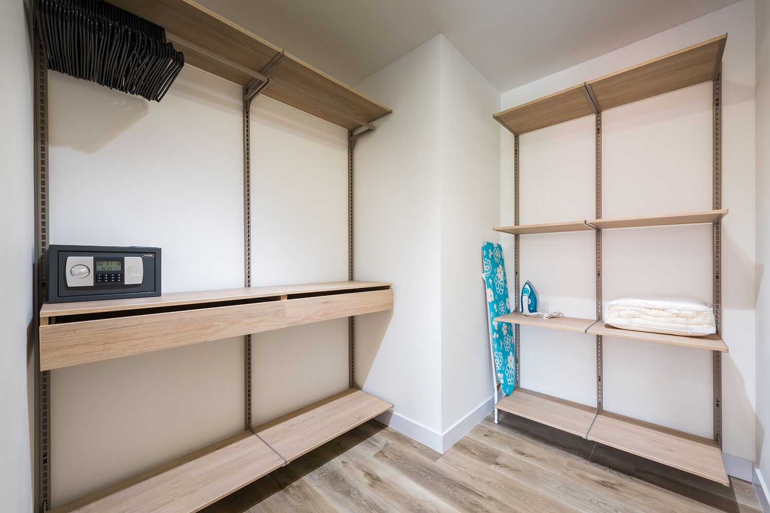 A storage closet with wooden shelves, a black radio, and a blue ironing board.