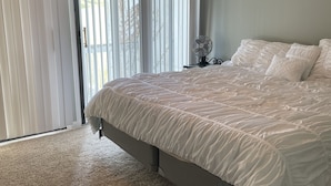 Een slaapkamer met een groot bed, een plafondventilator en uitzicht door het raam.