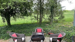 Een terras buiten met rieten meubilair en een barbecue.
