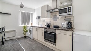 Een moderne keuken met een ingebouwde oven, magnetron en koffiezetapparaat op het aanrecht.