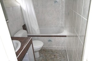 Une salle de bain équipée de toilettes, d’une baignoire et d’un rideau de douche.