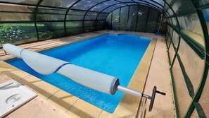 Una piscina con un colchoneta enrollada grande en el centro, rodeada por una estructura tipo invernadero.