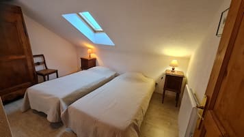 Une chambre avec deux lits, une lucarne et des lampes de chevet.