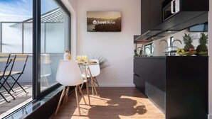 A modern kitchen with a large window, a dining area with a table and chairs, and a kitchen island with fruits. - Bright Flat w/ Balcony |  Ace Location by HostWise (Porto)