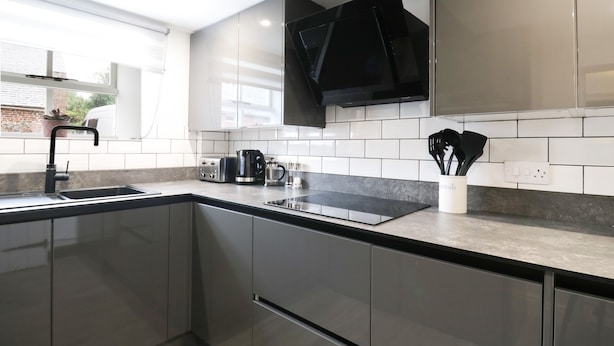 Una cocina moderna con electrodomésticos de acero inoxidable, una campana extractora negra y una ventana que da a un edificio de ladrillo.