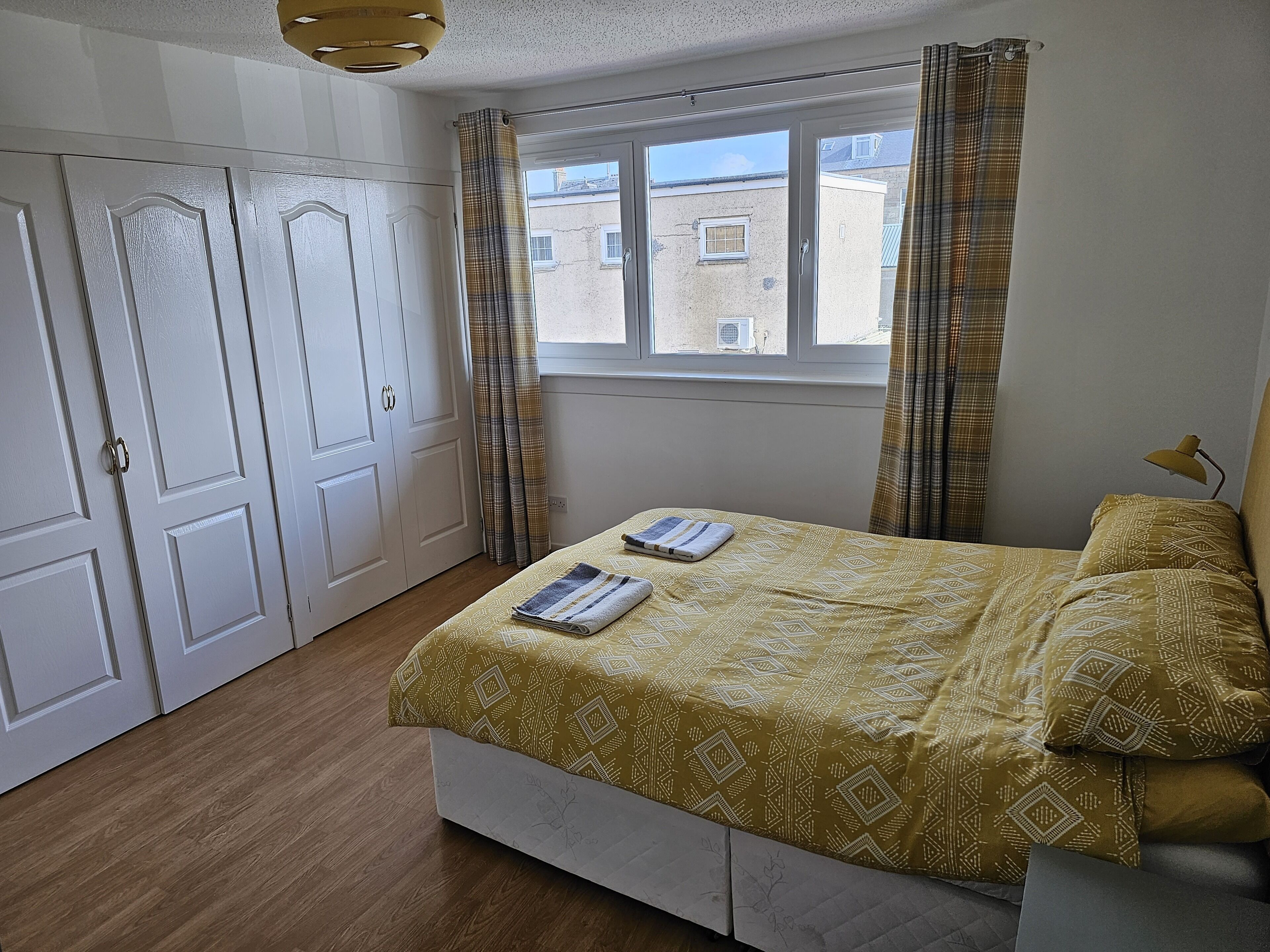 A bedroom with a bed, a window, curtains, and a door.