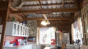 Une cuisine rustique avec un mur en pierre, des poutres en bois et une enseigne indiquant « LA FONDITA ».