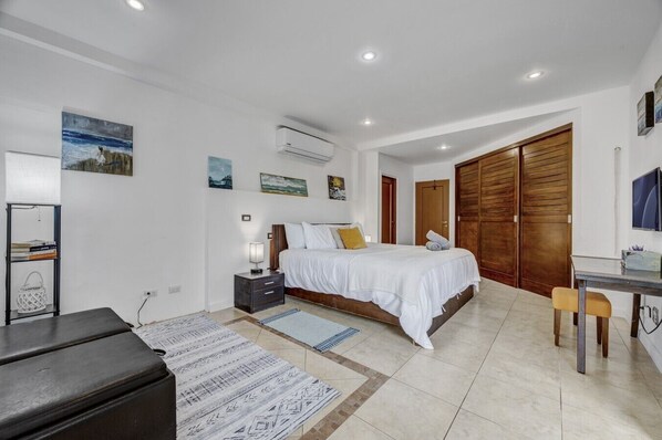 A bedroom with a bed, bedside table, lamp, and artwork on the wall.