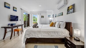 Ein Schlafzimmer mit einem Bett, einem Schreibtisch, einem Fernseher und Kunstwerken an den Wänden.