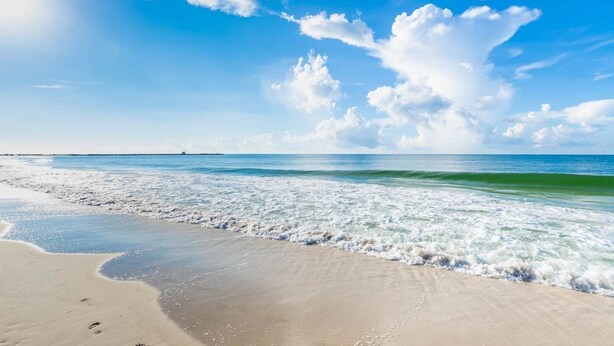Una playa con cielos despejados y olas.