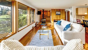 A spacious living room with a large window, a sofa, and a coffee table. - Serene La Conner Retreat w/ Fireplace & Deck! (La Conner)