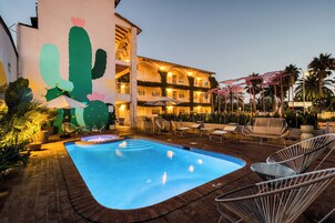 Una piscina al aire libre, sombrillas, sillones reclinables de piscina