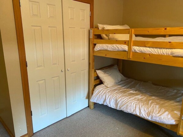 A room with a bunk bed, a white door, and a carpeted floor. - Red Rob #5 Red Mountain (Rossland)