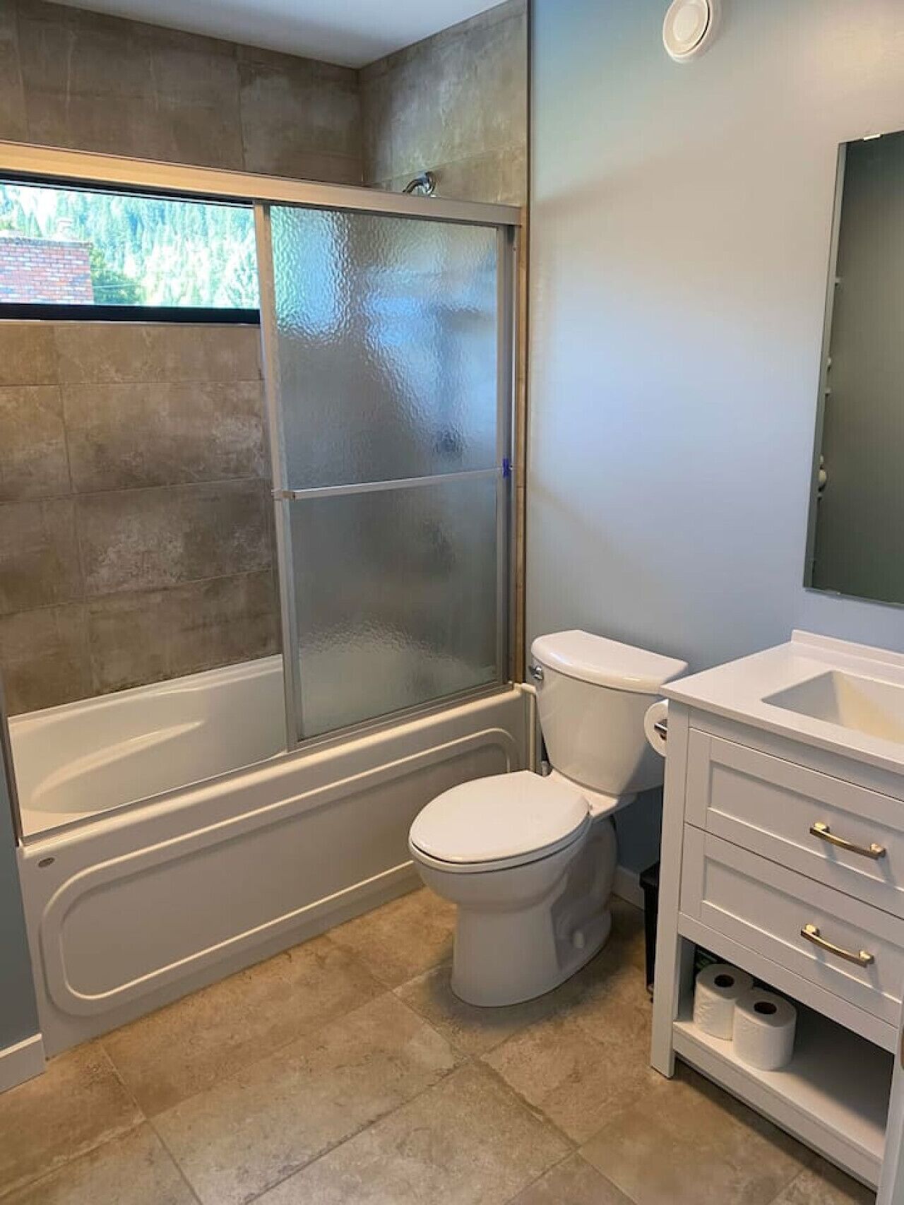 Ein Badezimmer mit einer gläsernen Duschkabine, einer Toilette und einem Waschtisch mit Schubladen.