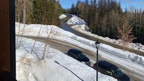 A snowy road with two cars parked on the side, surrounded by trees and a clear blue sky. - Redstone Chalets C Red Mountain (Rossland)