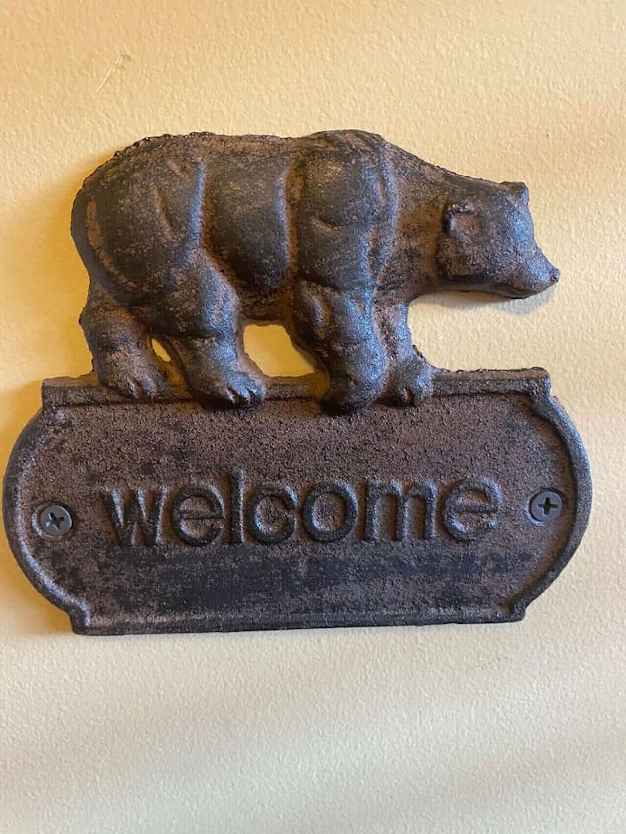 Une plaque d’accueil en métal ornée d’un motif d’ours.