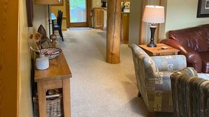 A spacious living area with a wooden dining table, a patterned sofa, and a view into the kitchen. - Copper Chalet 6 - sleeps 10 (Rossland)