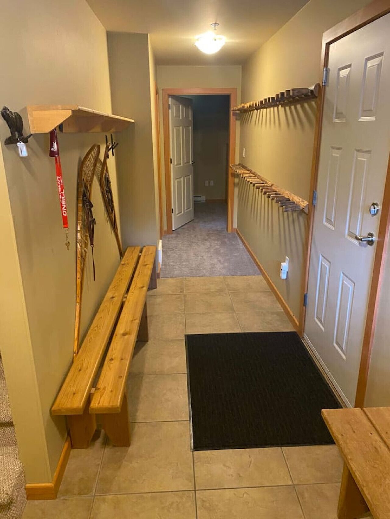 A hallway with a wooden bench, a coat rack, and a door.