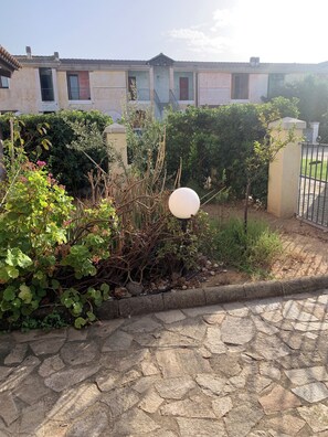 A stone-paved pathway leading to a building with a gated entrance.
