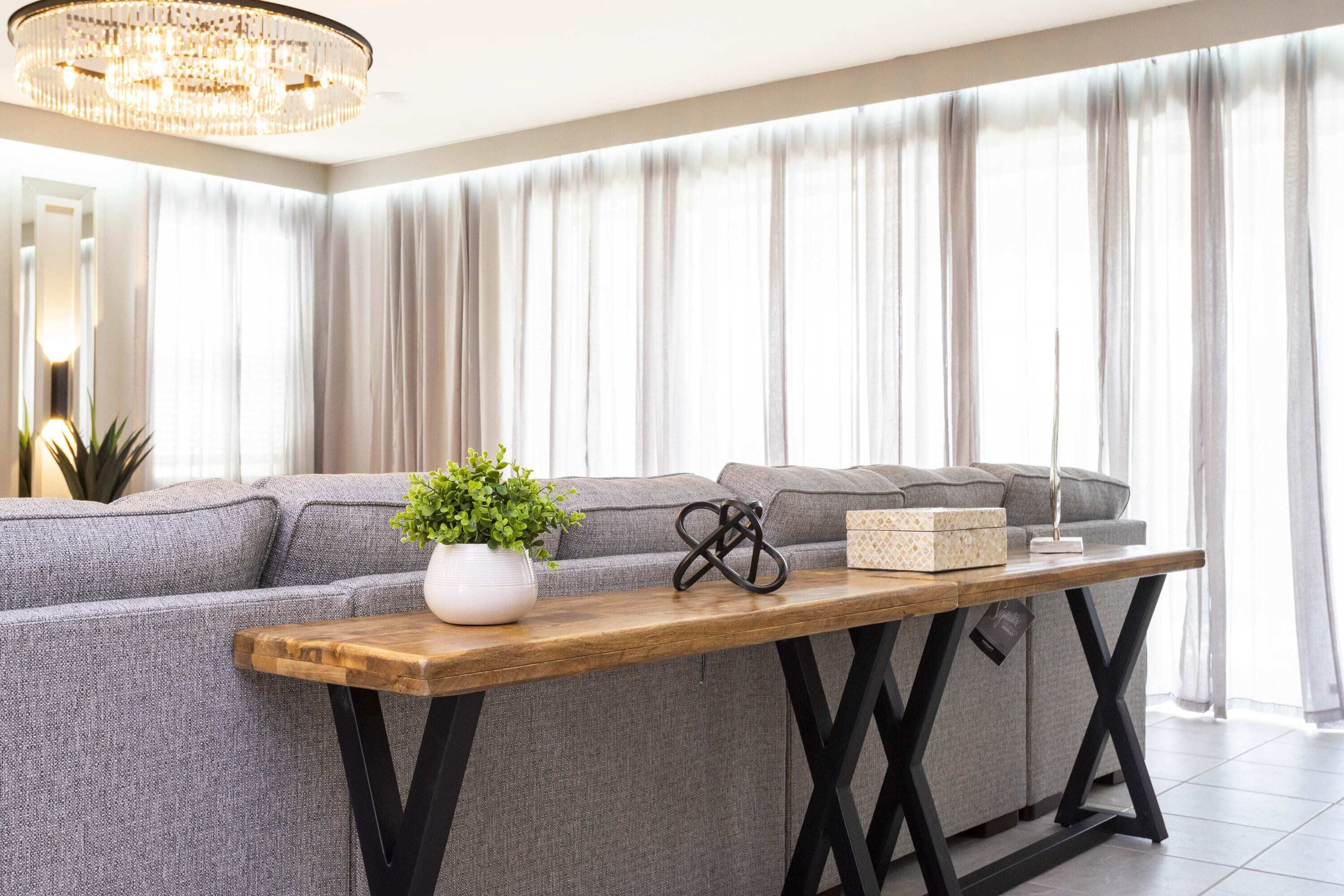 Een moderne woonkamer met een grijze modulaire bank, een houten salontafel en een kroonluchter.