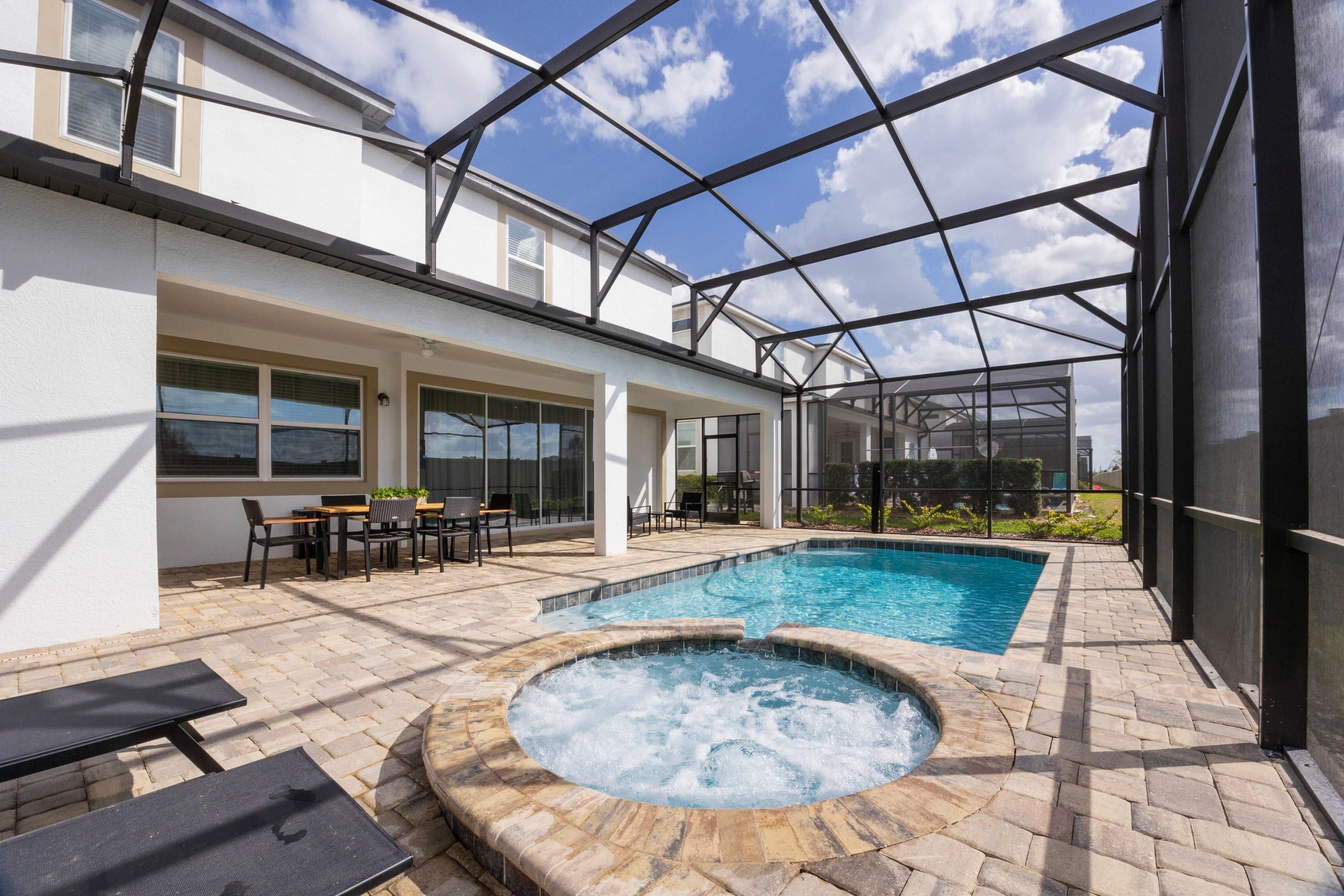 A pool area with a hot tub, outdoor seating, and a covered patio.