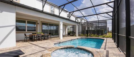 A pool area with a hot tub, outdoor seating, and a covered patio.