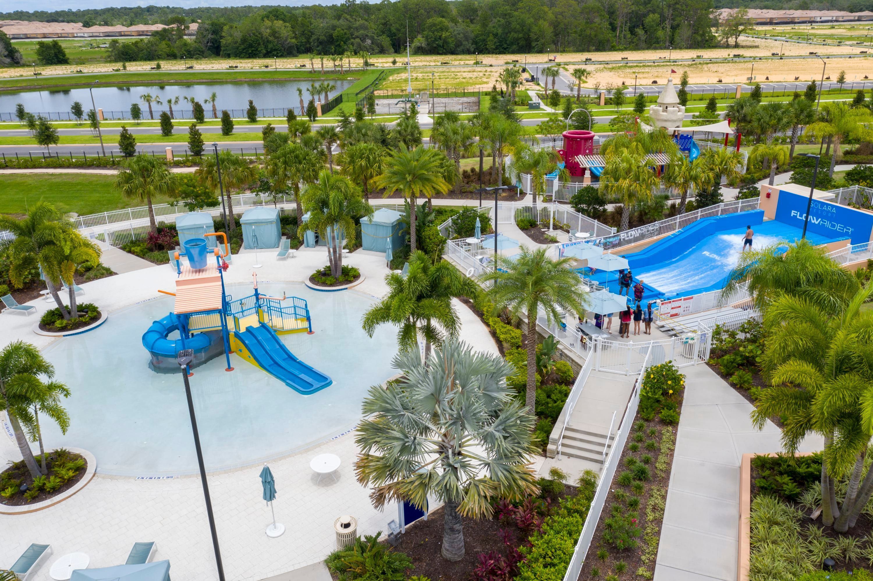 A water park with a large pool, slides, and palm trees.