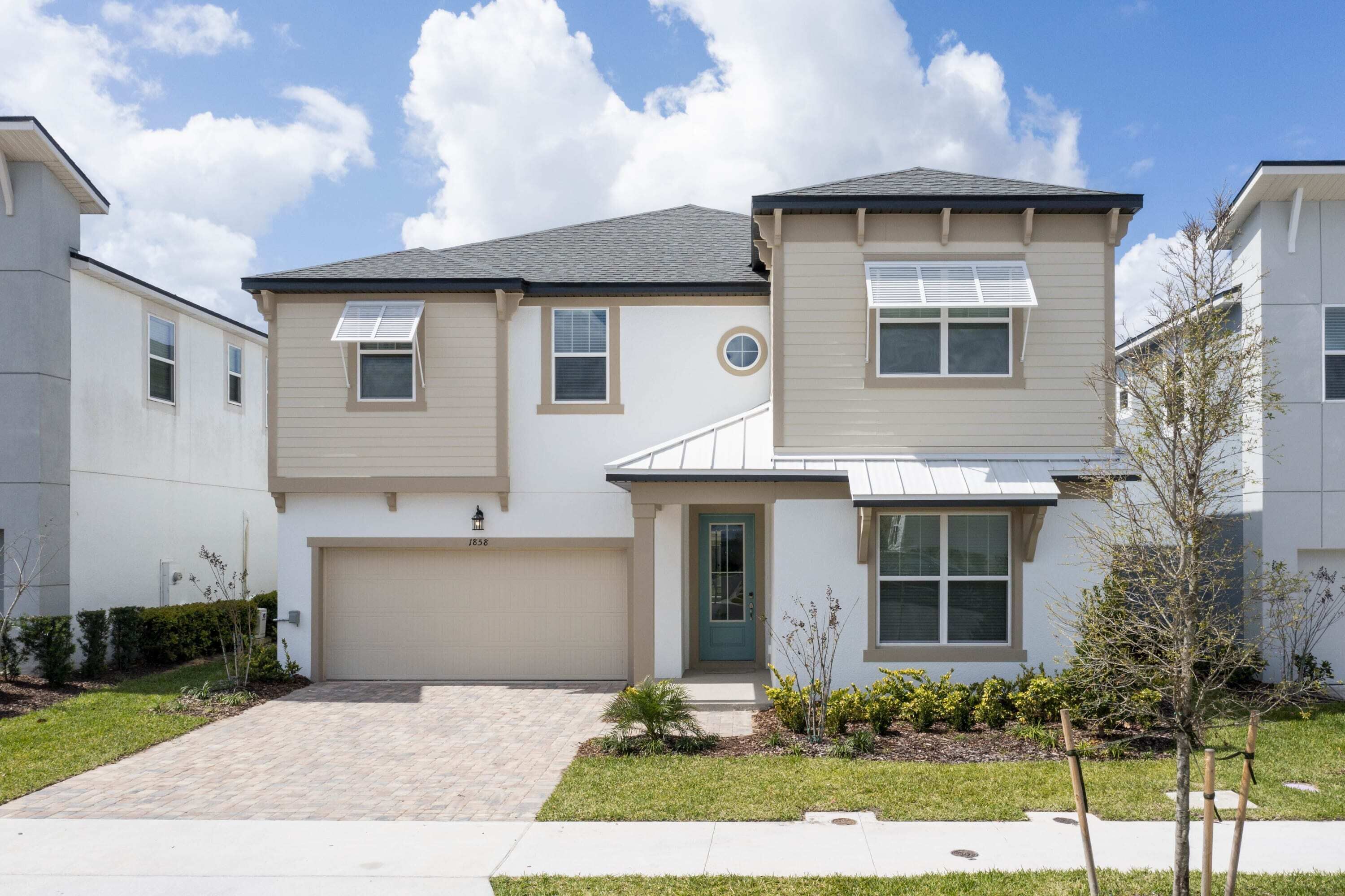 A two-story residential building with a garage, a front door, and a small front yard with landscaping.