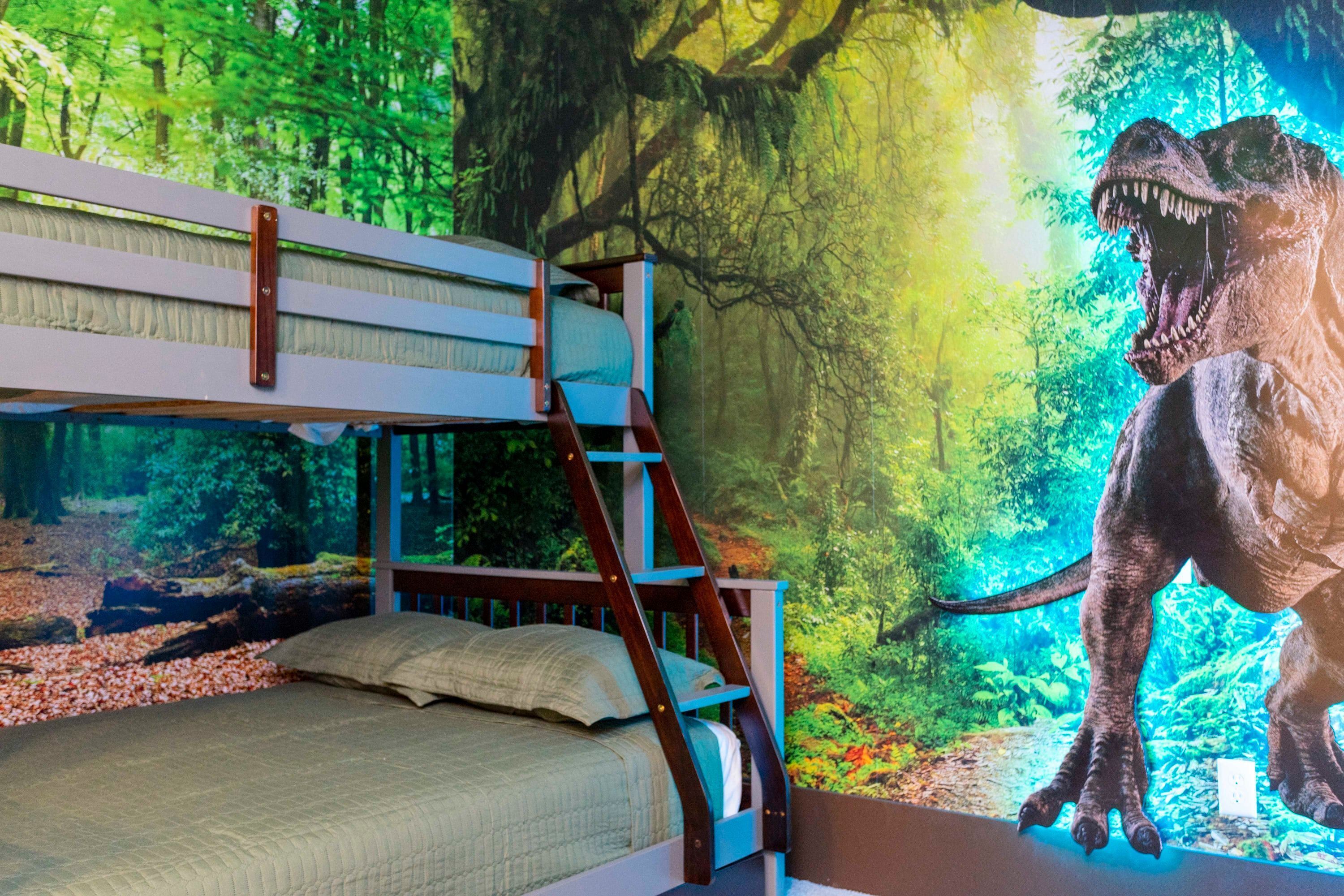 A bunk bed with a forest mural and a dinosaur statue.
