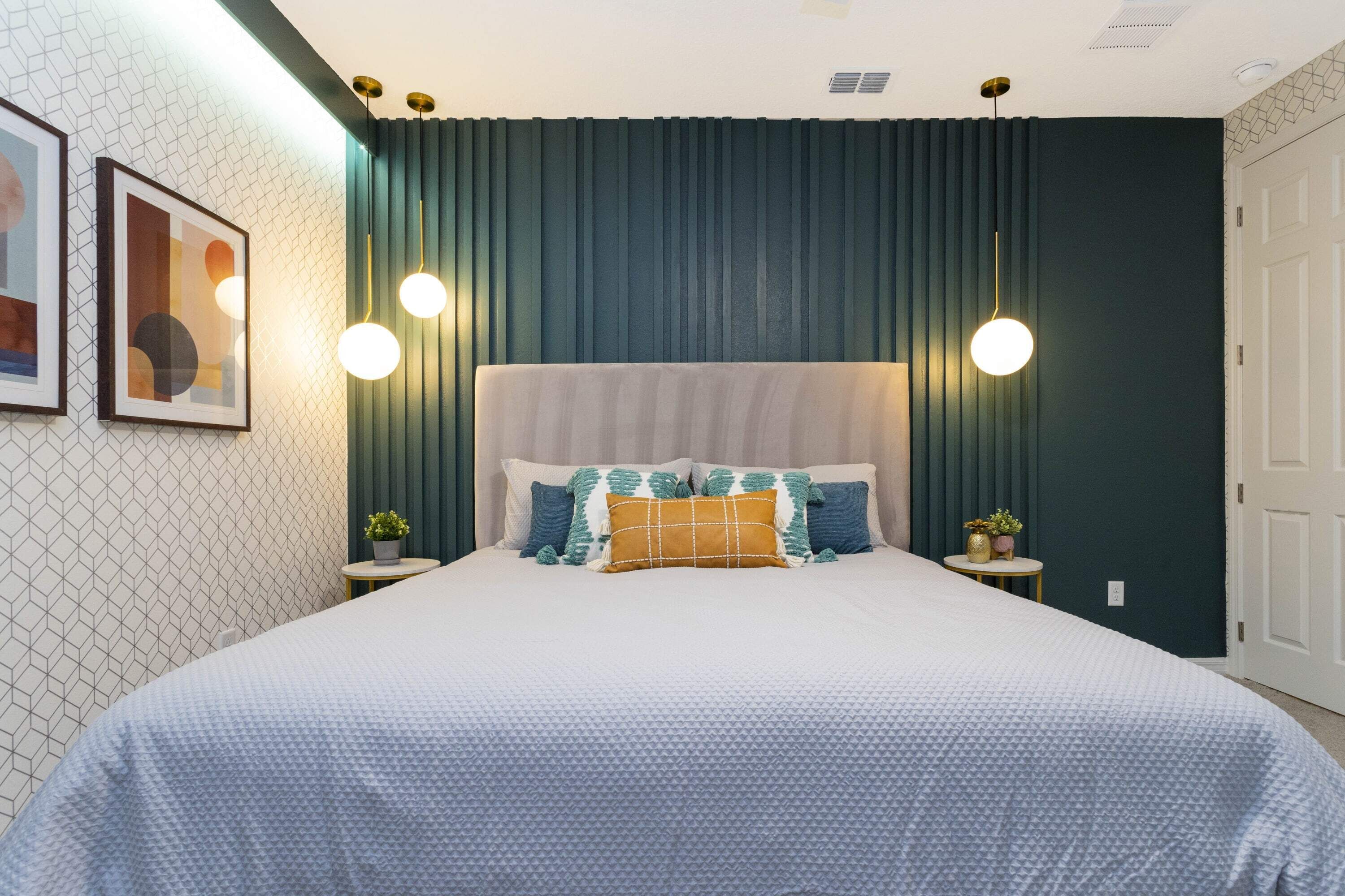 Une chambre bien rangée, avec un grand lit, deux tables de chevet et un luminaire fixé au mur.