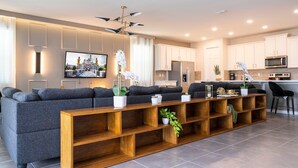 A modern living room with a grey sofa, wooden shelves, and a flat-screen TV. - Fabulous 9BD 6B Avatar Movie Harryporter Sleep24 (Kissimmee)