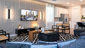 A modern living room with a flat-screen TV, a wooden coffee table, and a black ottoman. - Fabulous 9BD 6B Avatar Movie Harryporter Sleep24 (Kissimmee)
