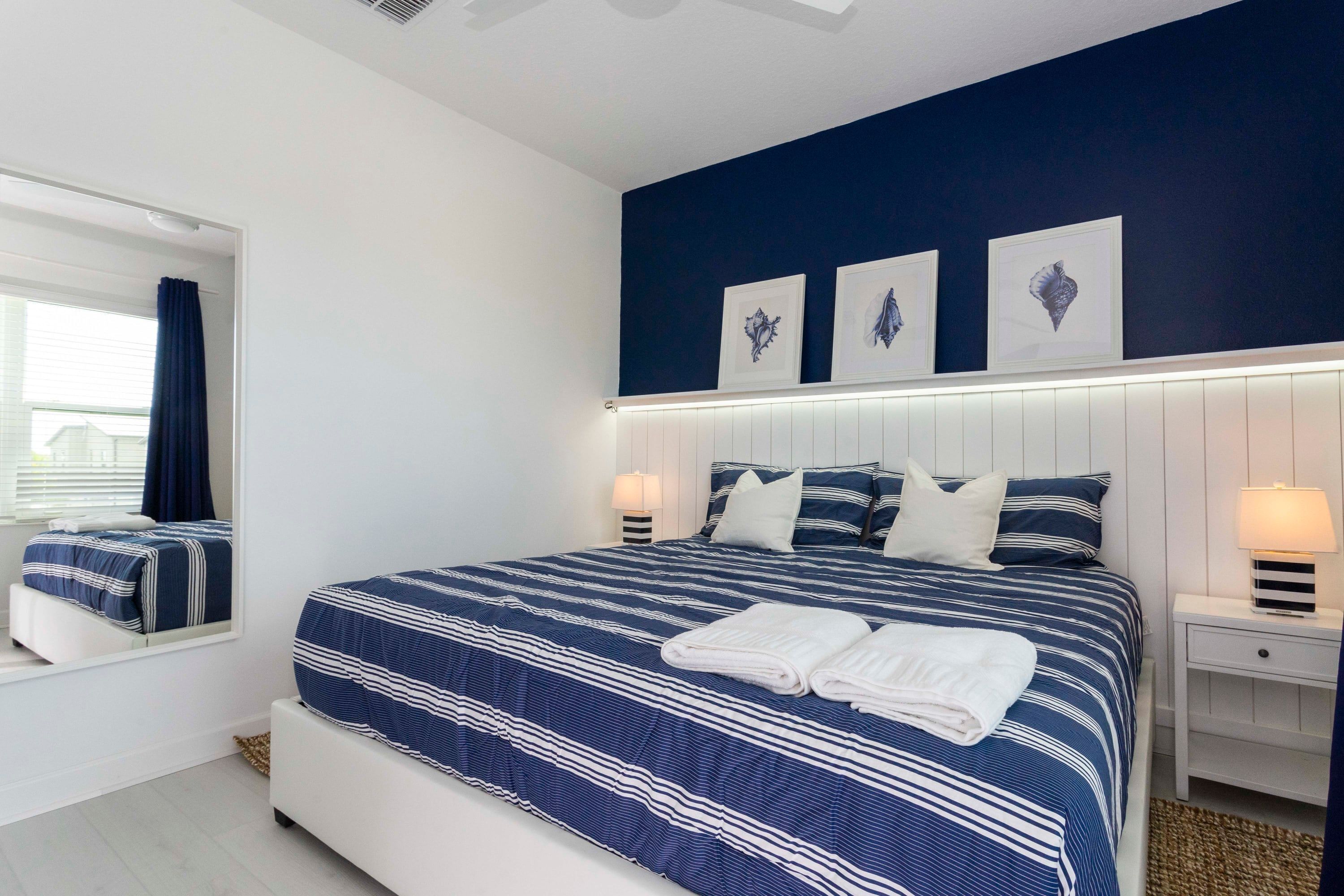 Une chambre à coucher avec un grand lit, une table de chevet avec une lampe et une fenêtre avec des rideaux.