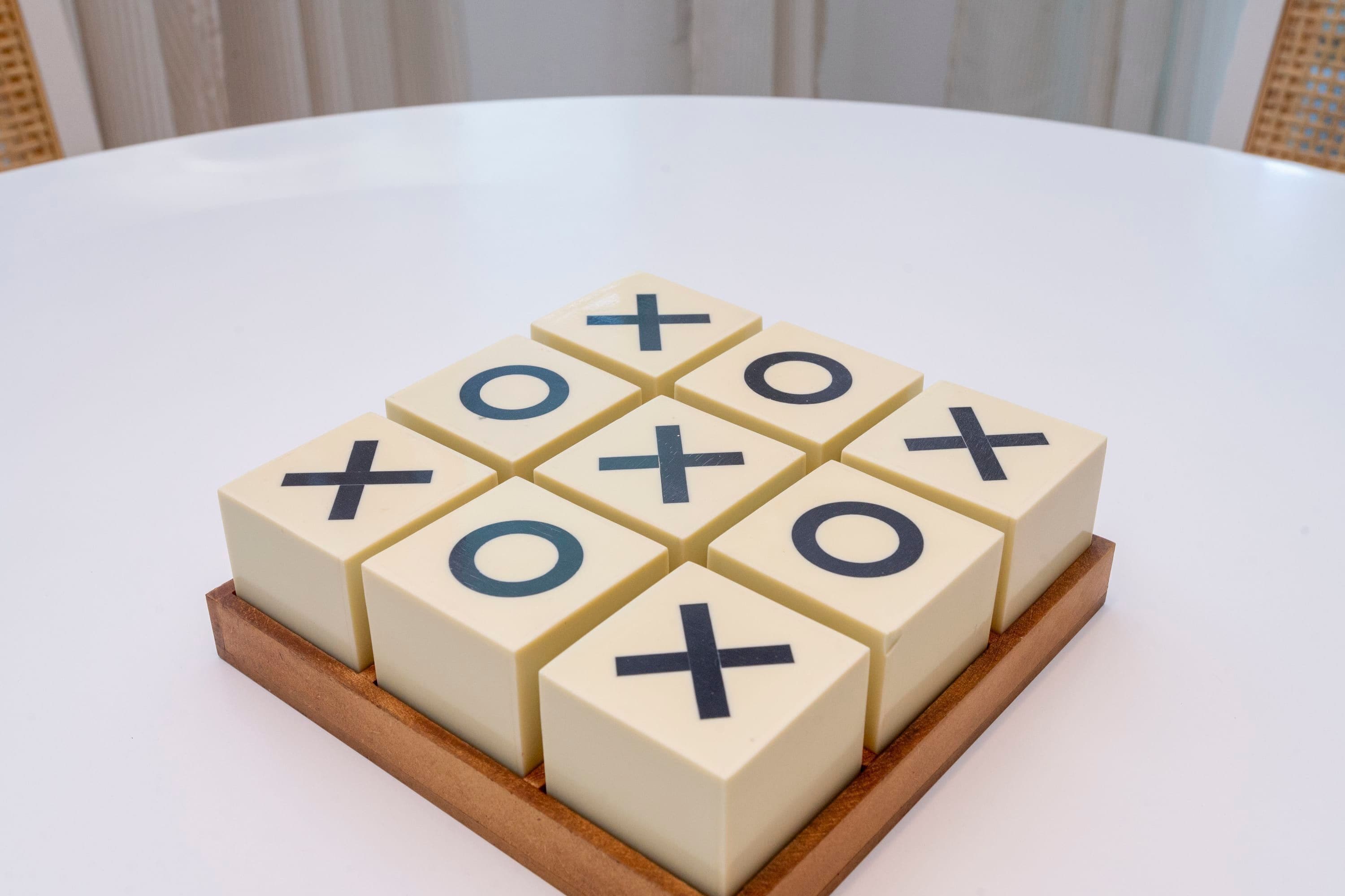 A tic-tac-toe game on a white table with a wooden base.