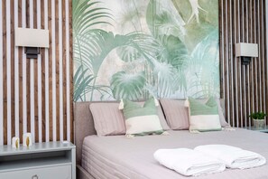 A bedroom with a bed, pillows, a nightstand, and a wall-mounted lamp.