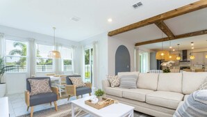 A spacious living area with a sofa, armchairs, and a coffee table. There is a dining area with a table and chairs, and a kitchen in the background. - Gorgeous 8B 7BA Melbournbeach w Pool Dock Beach (Melbourne Beach)