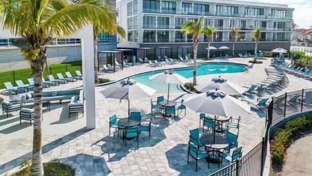 A modern hotel with a swimming pool, outdoor seating, and palm trees. - Gorgeous 8B 7BA Melbournbeach w Pool Dock Beach (Melbourne Beach)