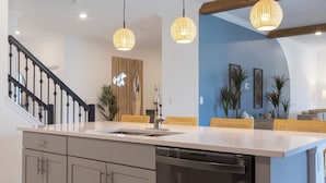 A modern kitchen with a white countertop, stainless steel dishwasher, and a wooden staircase. - Gorgeous 8B 7BA Melbournbeach w Pool Dock Beach (Melbourne Beach)