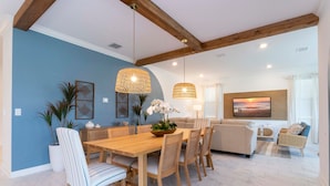 A dining area with a wooden table and chairs, a blue accent wall, and hanging wicker lamps. - Gorgeous 8B 7BA Melbournbeach w Pool Dock Beach (Melbourne Beach)