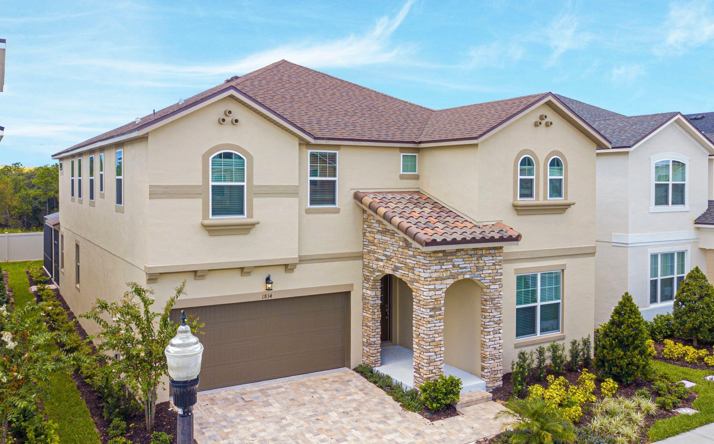 A two-story house with a stone archway entrance, a garage, and a well-maintained garden.