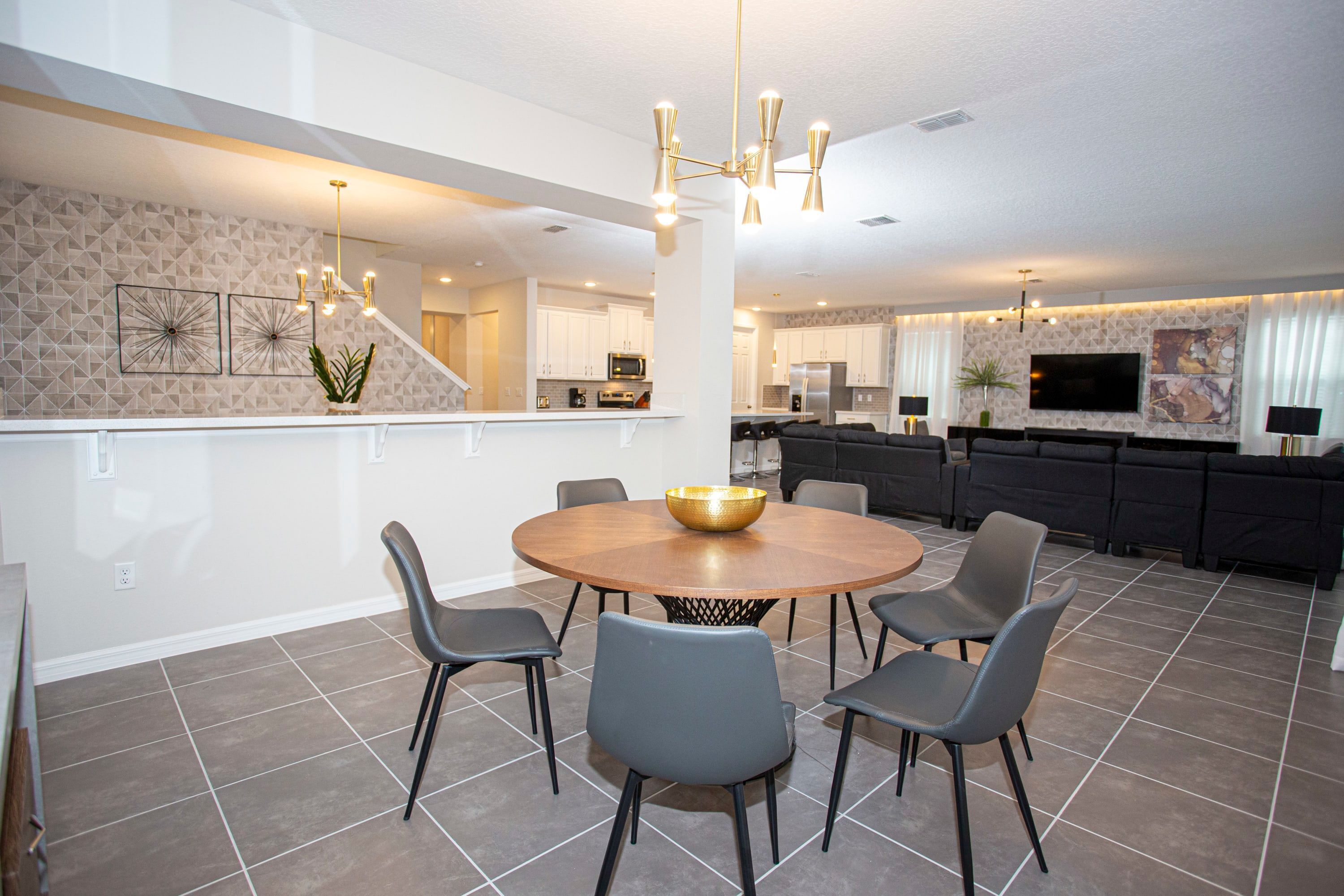 A modern kitchen with white cabinets, a central island, and a dining area with a round table and chairs.