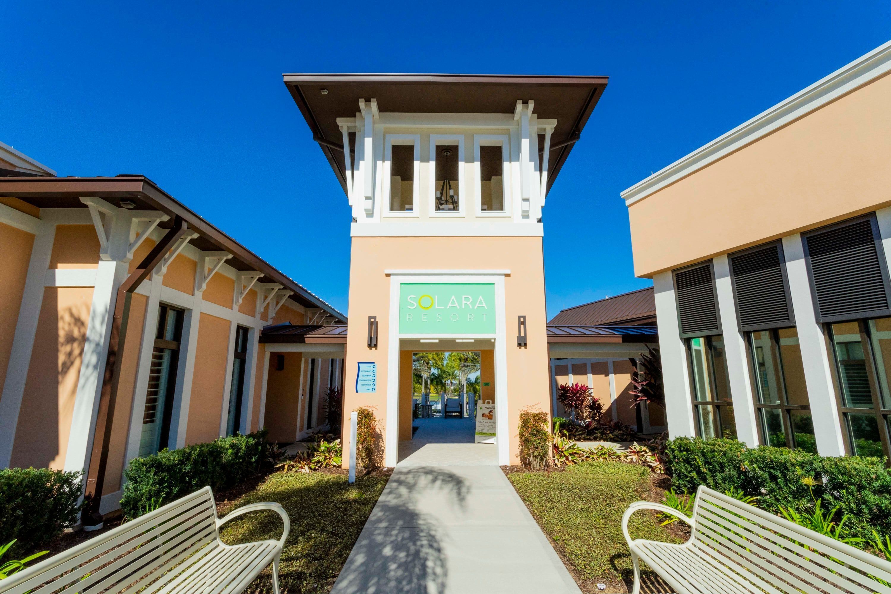 The entrance to Solara Resort with a central tower, a pathway, and benches.