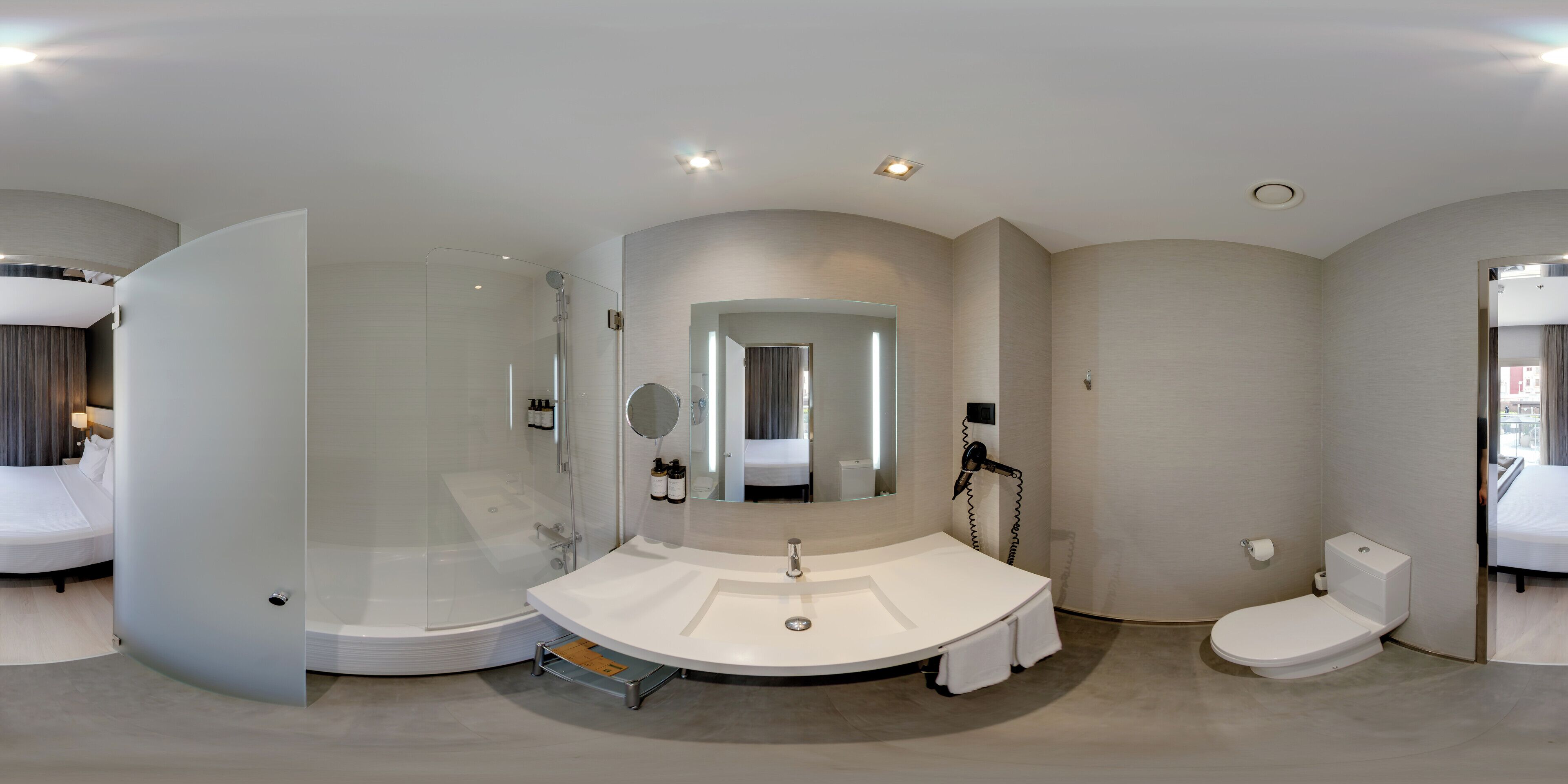 Une salle de bain moderne avec une douche à parois de verre, un lavabo rond, des toilettes et un grand miroir.