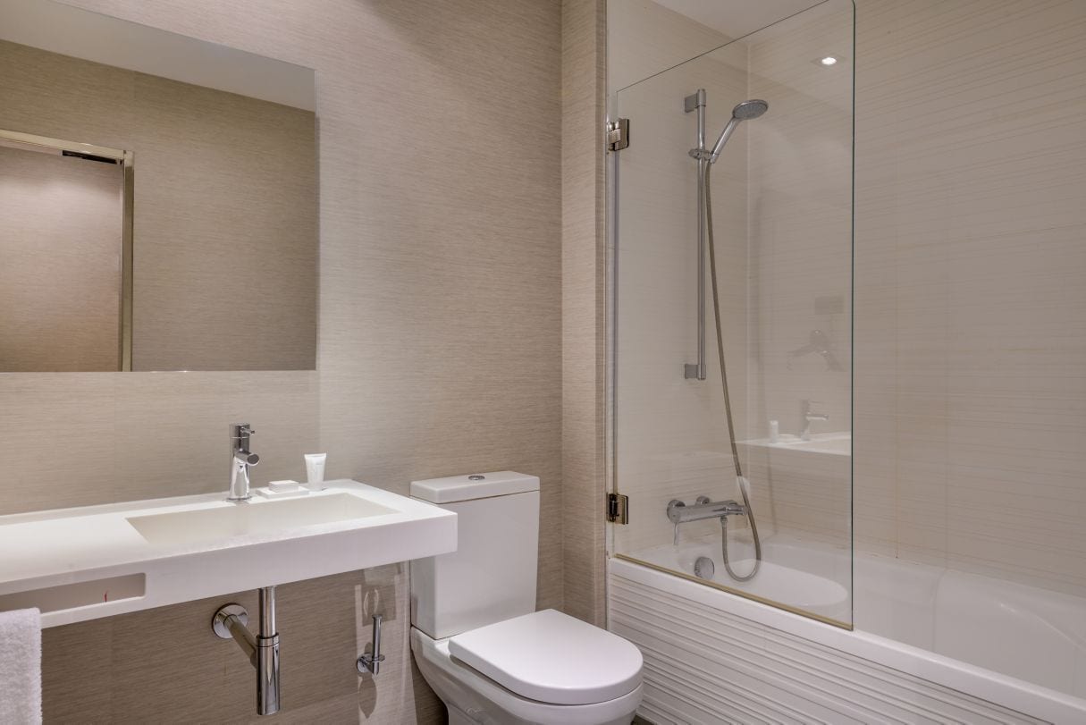 A modern bathroom with a white sink, toilet, and glass-enclosed shower area.