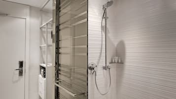 Un baño moderno con cabina de ducha de vidrio, inodoro empotrado y pared de azulejos blancos.