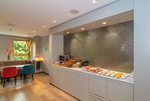 A modern dining area with a buffet setup, a sofa, and a window with natural light.